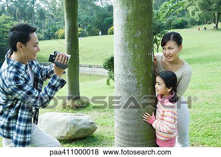 Man videotaping wife and daughter in park View Large Photo Image Stock Photo - Man videotaping wife and daughter in park. Fotosearch