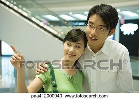 Couple in mall, woman pointing View Large Photo Image Stock Image - Couple in mall, woman pointing. Fotosearch
