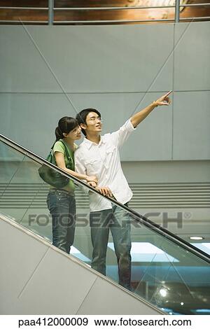 Couple on escalator, man pointing View Large Photo Image Stock Photo - Couple on escalator, man pointing. Fotosearch