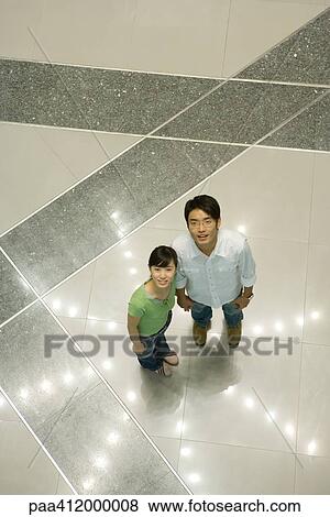 Couple standing on star-shaped light pattern on floor, high angle view View Large Photo Image Stock Photo - Couple standing on star-shaped light pattern on floor, high angle view. Fotosearch
