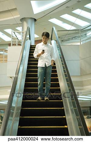 Man on escalator checking cell phone View Large Photo Image Picture - Man on escalator checking cell phone. Fotosearch