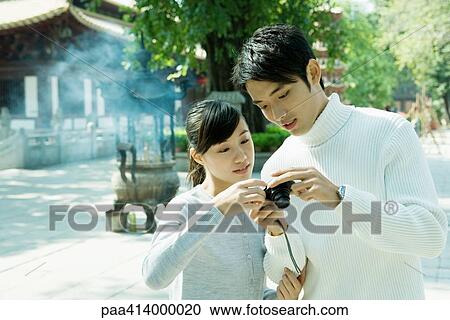 Couple looking at digital camera, temple in background View Large Photo Image Stock Image - Couple looking at digital camera, temple in background. Fotosearch