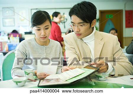 Couple looking at menu in restaurant View Large Photo Image Picture - Couple looking at menu in restaurant. Fotosearch