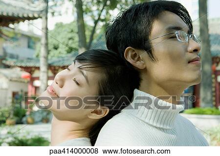 Couple sitting back to back, traditional Chinese buildings in background View Large Photo Image Stock Photo - Couple sitting back to back, traditional Chinese buildings in background. Fotosearch