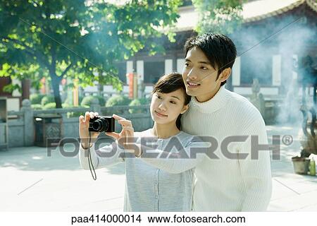 Couple taking photo, temple in background View Large Photo Image Picture - Couple taking photo, temple in background. Fotosearch