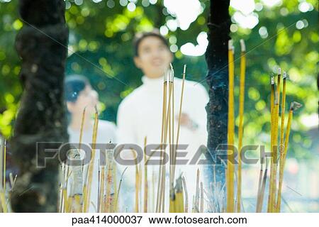 Incense burning, couple standing in blurred background View Large Photo Image Stock Photo - Incense burning, couple standing in blurred background. Fotosearch