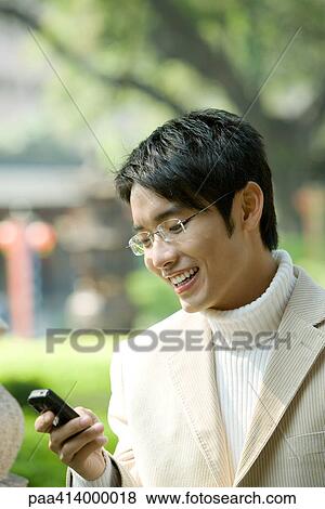 Man looking at cell phone, smiling View Large Photo Image Stock Photo - Man looking at cell phone, smiling. Fotosearch