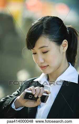 Woman holding cell phone, looking down at wrist View Large Photo Image Stock Photo - Woman holding cell phone, looking down at wrist. Fotosearch