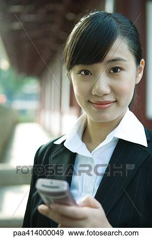 Woman holding cell phone, smiling at camera, portrait View Large Photo Image Stock Photo - Woman holding cell phone, smiling at camera, portrait. Fotosearch
