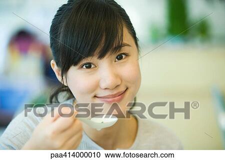 Woman holding up spoon, smiling at camera View Large Photo Image Stock Image - Woman holding up spoon, smiling at camera. Fotosearch