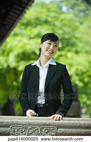 Woman standing holding cell phone View Large Photo Image Stock Photography - Woman standing holding cell phone. Fotosearch