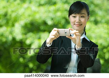 Stock Image - Woman taking photo with phone. Fotosearch