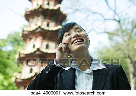 Woman using cell phone, pagoda in background View Large Photo Image Stock Image - Woman using cell phone, pagoda in background. Fotosearch