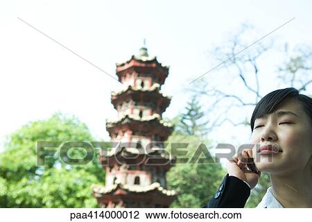 Woman using cell phone, pagoda in background View Large Photo Image Stock Image - Woman using cell phone, pagoda in background. Fotosearch