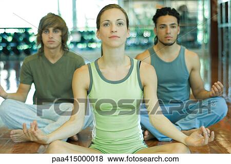 Stock Photo - Yoga class, young adults sitting in lotus position. Fotosearch