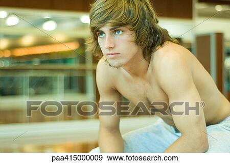 Stock Photo - Young man sitting barechested in gym room. Fotosearch