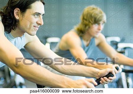 Men riding exercise bikes View Large Photo Image Stock Photo - Men riding exercise bikes. Fotosearch