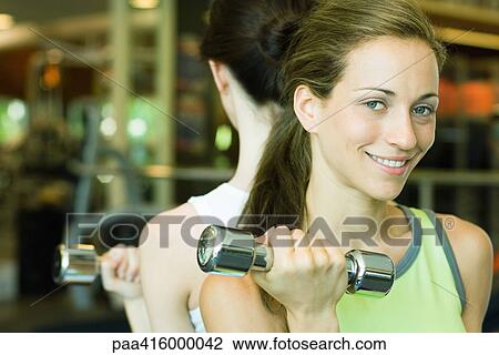 Two women lifting dumbbells, back to back View Large Photo Image Stock Image - Two women lifting dumbbells, back to back. Fotosearch