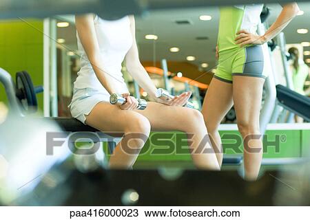 Two women standing in weight room, partial view View Large Photo Image Stock Image - Two women standing in weight room, partial view. Fotosearch