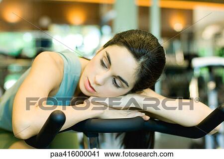 Stock Image - Woman resting on exercise bike. Fotosearch
