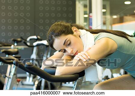 Stock Photo - Woman resting on exercise bike. Fotosearch