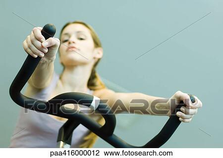 Stock Image - Woman riding exercise bike. Fotosearch