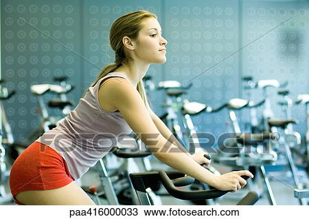 Stock Image - Woman riding exercise bike. Fotosearch