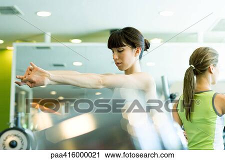 Woman stretching arms in health club View Large Photo Image Stock Image - Woman stretching arms in health club. Fotosearch