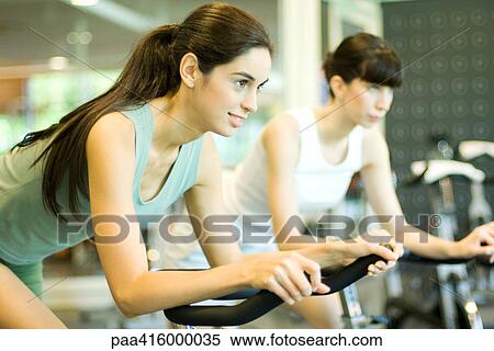 Stock Photography - Women riding exercise bikes. Fotosearch