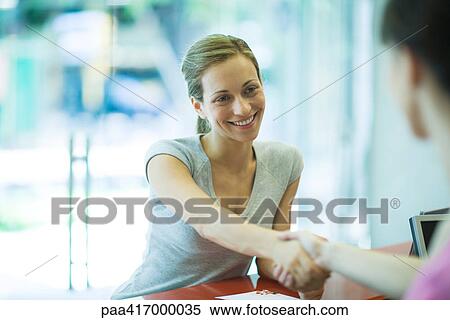 Two women shaking hands across counter View Large Photo Image Stock Photography - Two women shaking hands across counter. Fotosearch