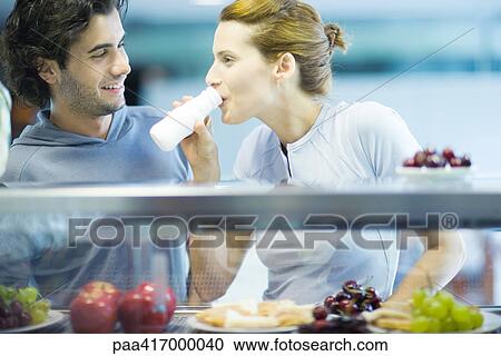 Young adults in exercise clothing, having snack in health club cafeteria View Large Photo Image Stock Image - Young adults in exercise clothing, having snack in health club cafeteria. Fotosearch