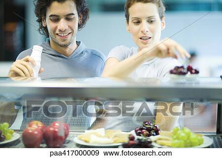 Young adults in exercise clothing, choosing snack in health club cafeteria View Large Photo Image Stock Photo - Young adults in exercise clothing, choosing snack in health club cafeteria. Fotosearch