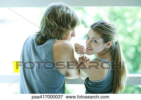 Young adults in exercise clothing standing side by side, woman looking over shoulder at camera View Large Photo Image Stock Photo - Young adults in exercise clothing standing side by side, woman looking over shoulder at camera. Fotosearch
