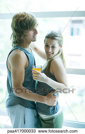 Young couple in exercise clothing, woman holding drink, man holding woman around waist View Large Photo Image Stock Image - Young couple in exercise clothing, woman holding drink, man holding woman around waist. Fotosearch