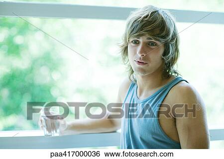 Young man in exercise clothing, holding glass of water View Large Photo Image Stock Photograph - Young man in exercise clothing, holding glass of water. Fotosearch