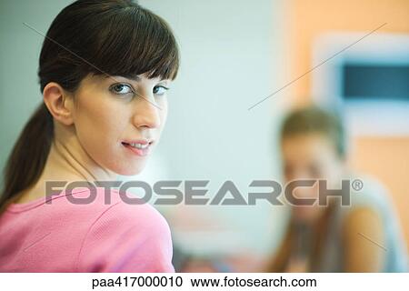 Young woman looking over shoulder at camera View Large Photo Image Stock Image - Young woman looking over shoulder at camera. Fotosearch