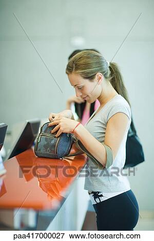 Young woman standing at counter of health club, looking through bag View Large Photo Image Stock Photo - Young woman standing at counter of health club, looking through bag. Fotosearch