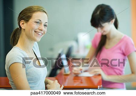 Stock Photo - Young women signing in at counter of health club. Fotosearch