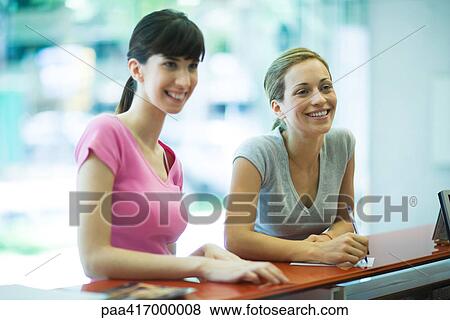 Stock Photo - Young women standing at counter of health club. Fotosearch