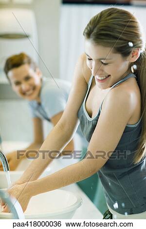 Stock Photograph - Two women washing hands in sinks, one getting splashed. Fotosearch