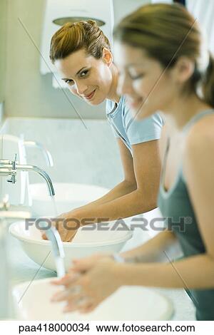 Two women washing hands in sinks View Large Photo Image Picture - Two women washing hands in sinks. Fotosearch