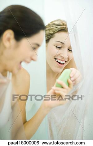 Stock Photograph - Two young women in showers, one handing bar of soap to the second. Fotosearch