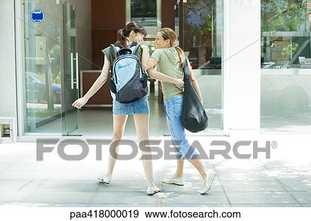 Two young women in street clothes walking towards entrance to health club View Large Photo Image Stock Photo - Two young women in street clothes walking towards entrance to health club. Fotosearch
