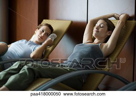 Two young women relaxing in lounge chairs View Large Photo Image Stock Image - Two young women relaxing in lounge chairs. Fotosearch