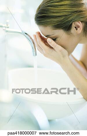 Stock Photo - Woman washing face over sink. Fotosearch