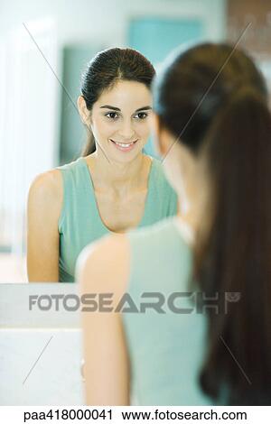 Young woman looking at self in mirror View Large Photo Image Stock Image - Young woman looking at self in mirror. Fotosearch