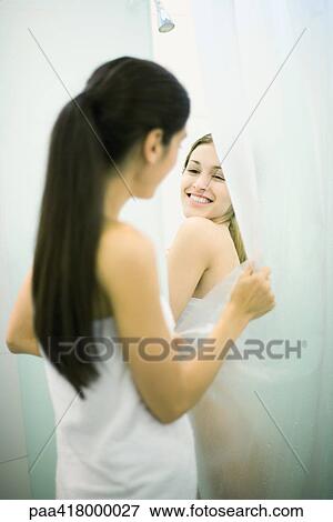 Stock Photo - Young woman taking shower while friend holds open shower curtain. Fotosearch