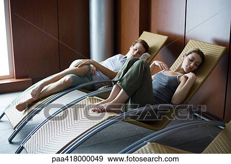 Stock Photo - Young women relaxing in lounge chairs. Fotosearch