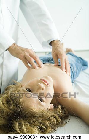 Doctor examining boy, boy looking at camera View Large Photo Image Stock Photo - Doctor examining boy, boy looking at camera. Fotosearch