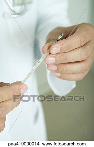 Doctor holding thermometer, close-up of hands View Large Photo Image Picture - Doctor holding thermometer, close-up of hands. Fotosearch
